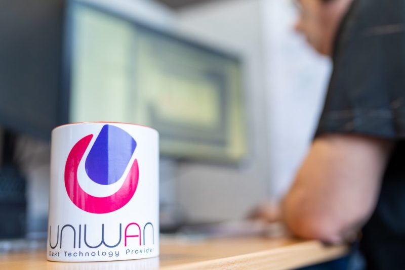 Tasse aux couleurs d'Uniwan avec en fond un consultant en cybersécurité